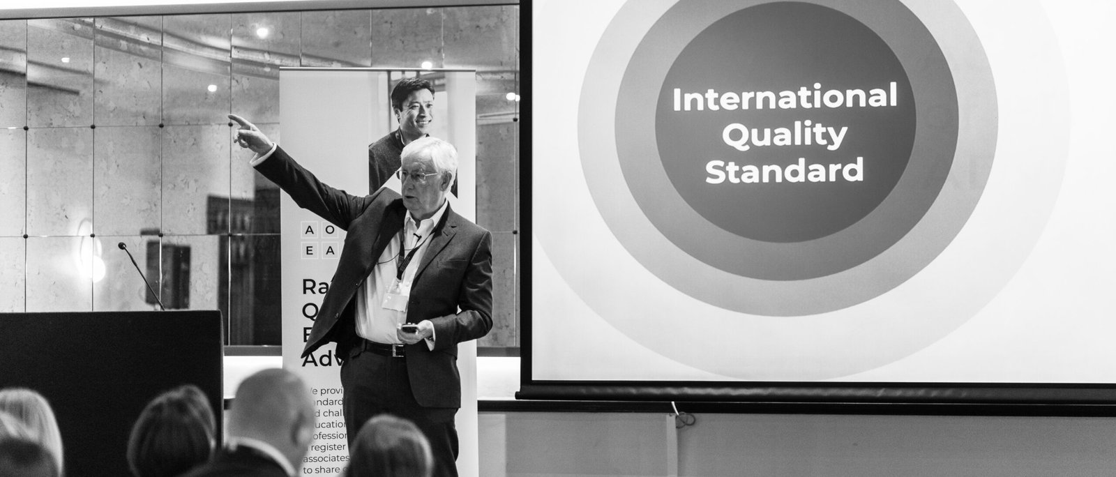 Les Walton speaking to an audience about the International Quality Standard